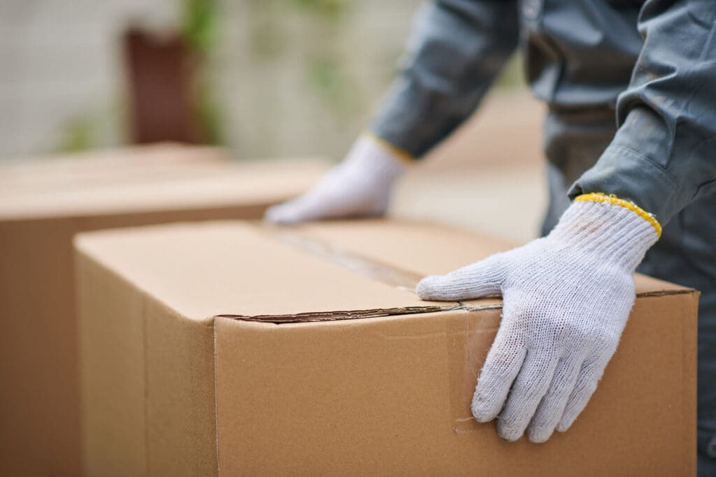 gloved hands holding a cardboard box